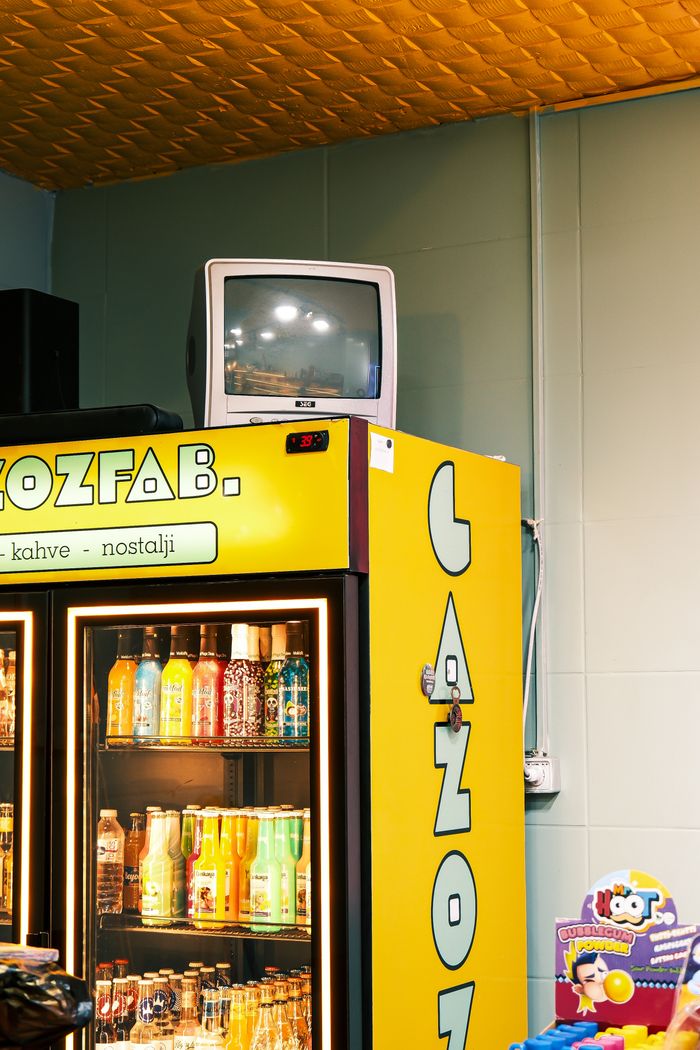 why-choose-us-02 A yellow vending machine with a vintage TV on top, filled with colorful drinks in a nostalgic setting.