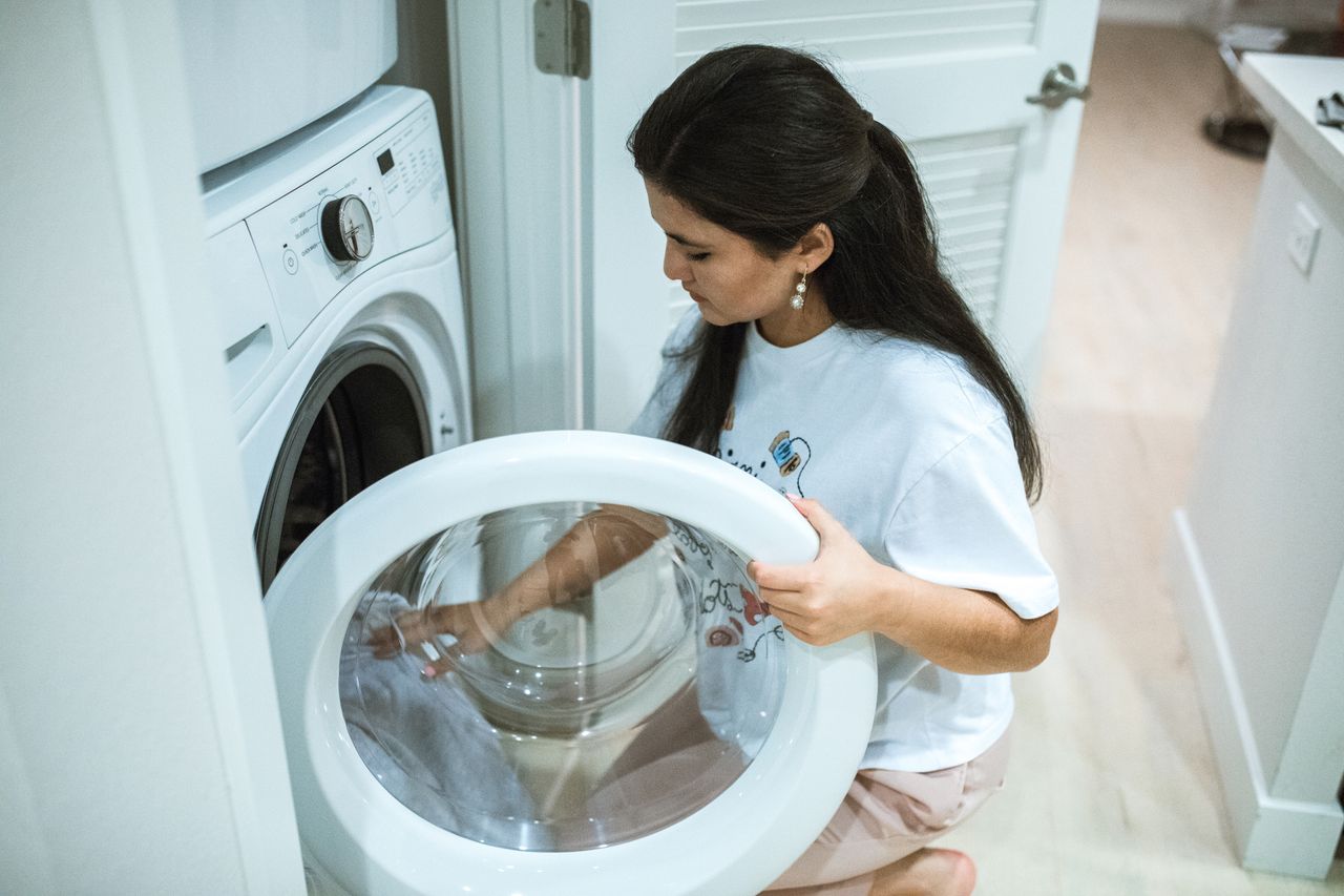 Crafting Captivating Headlines: Your awesome post title goes here A woman kneeling to load clothes into a front-loading washing machine in a modern home laundry room.